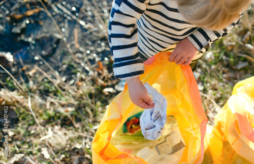 Unrecognizable small child collecting rubbish outdoors in nature, plogging concept.