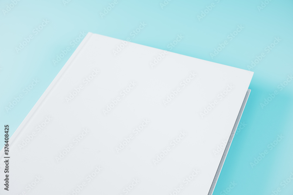 Creative closed white hardcover book on blue background. Creative closed white hardcover book on blue background.