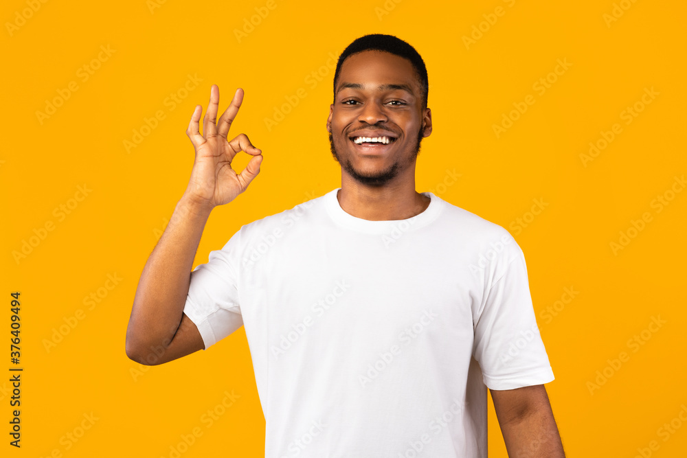 Positive African Man Gesturing OK Sign On Yellow Studio Background Positive African Man Gesturing OK Sign On Yellow Studio Background