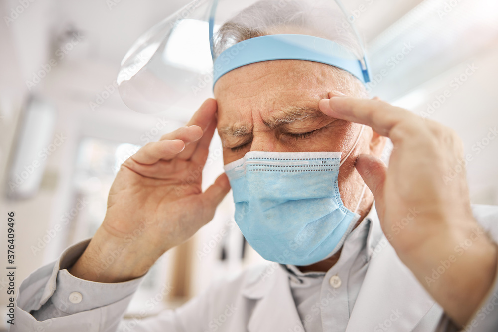 Fototapeta premium Elderly healthcare professional touching his head and frowning