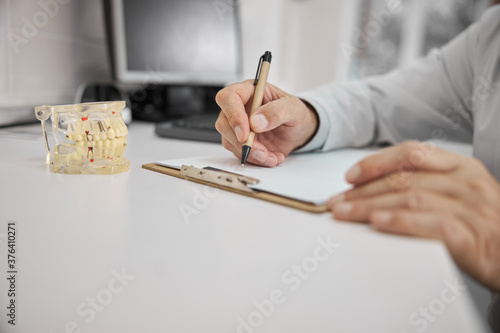 Dentist writing a prescription for dental implant