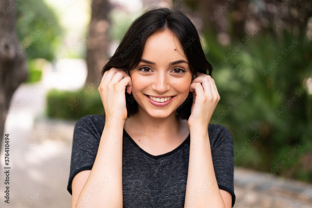 Young sport caucasian woman listening music at outdoors in a park