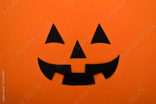 Black eyes,nose and mouth of black paper on an orange background.Halloween concept.