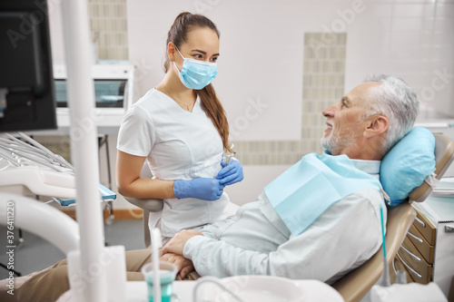 Friendly female dentist looking at her elderly patient