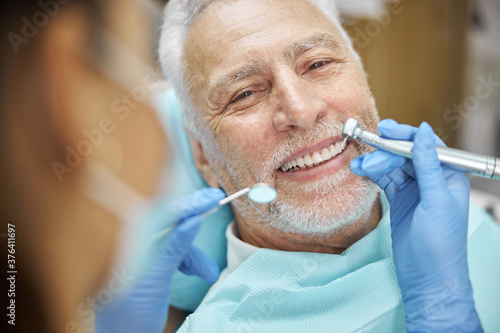 Bild auf Leinwand Mirthful senior citizen smiling during a dental treatment