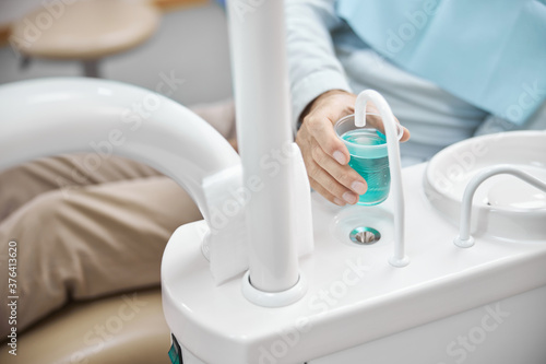Patient of a dental clinic getting some water to rinse his mouth