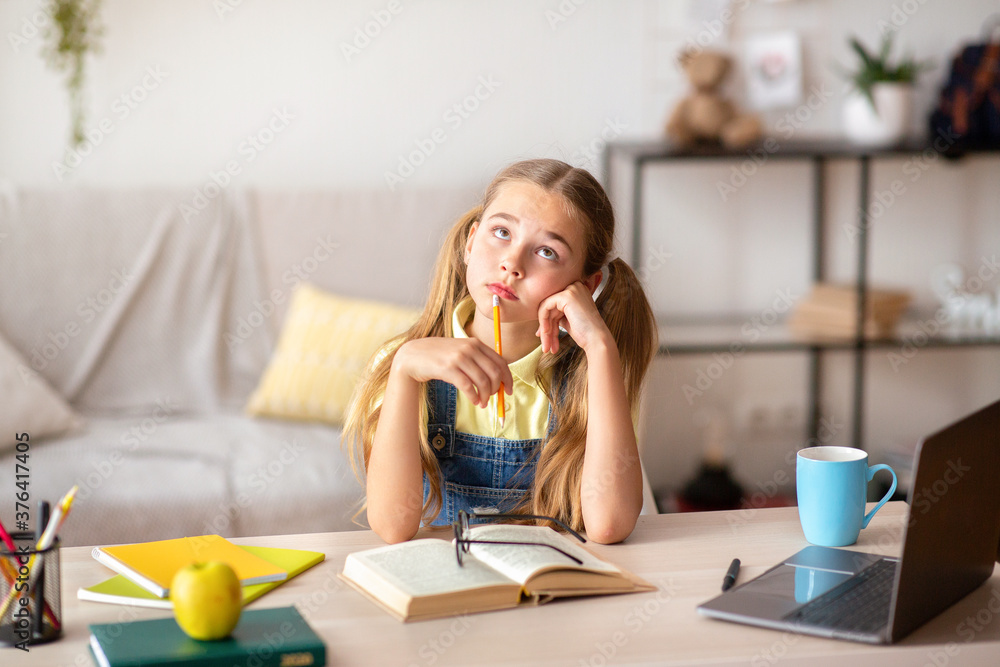 Pensive girl sitting at desk, doing hometask Pensive girl sitting at desk, doing hometask