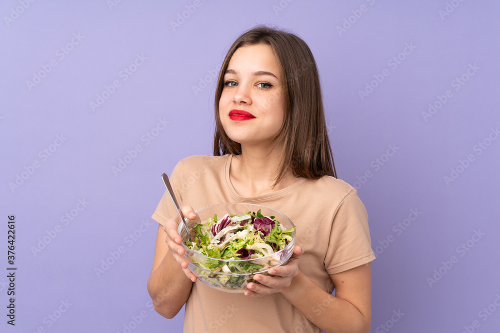 Teenager girl holding salad isolated on purple background Teenager girl holding salad isolated on purple background