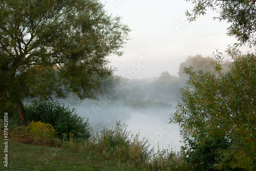 Peaceful early morning mist rolling over quiet lake.