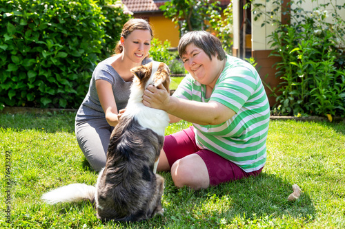 Fototapete mentally disabled woman with a second woman and a companion dog