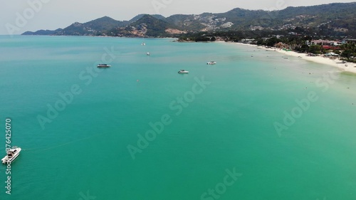 Motor yachts in blue sea on resort. Modern motor yachts floating on calm surface of blue sea near beach on sunny day on tropical resort. Koh Samui paradise exotic Chaweng beach drone view.