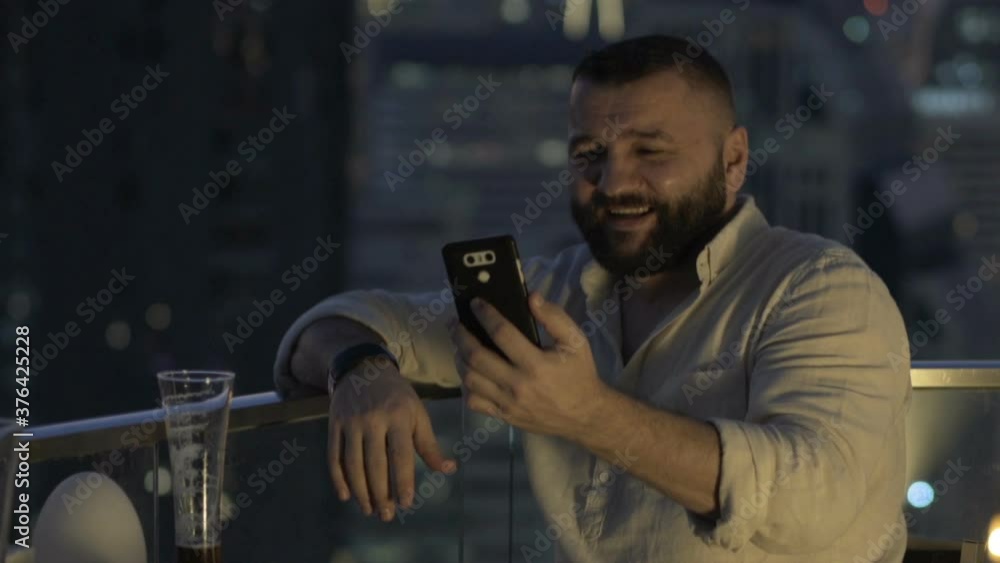 Young man video chat on smartphone and drink beer in luxury bar Young man video chat on smartphone and drink beer in luxury bar