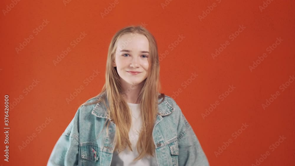 Happy girl jumps for joy and laughs. The joy of winning, winning. Looks into the camera. Orange background. Happy girl jumps for joy and laughs. The joy of winning, winning. Looks into the camera. Orange background.