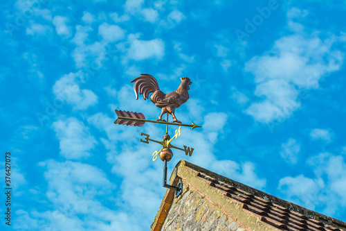 Copper cockerel, rooster or chicken weather vane on a farm with blue sky background