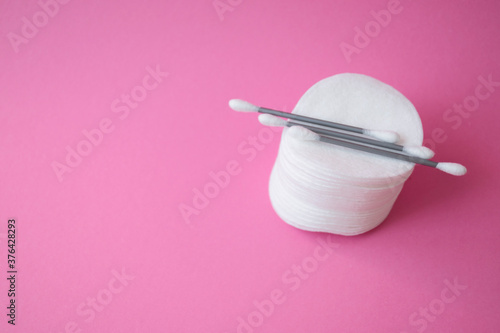 Clean cotton buds for cleaning ears and cotton pads for removing make up and washing face on pink background. Personal care and hygiene products concept. Copy space.