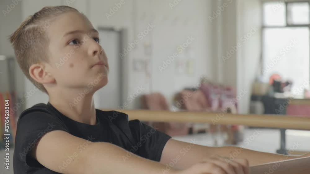 Performs ballet exercises, leg back. Dance school training. The boy looks ahead. Performs ballet exercises, leg back. Dance school training. The boy looks ahead.