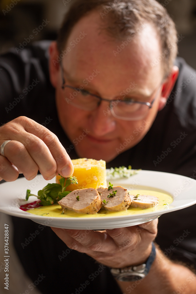 Chef in hotel or restaurant kitchen cooking only hands. He is working on the micro herb and preparing main course Chef in hotel or restaurant kitchen cooking only hands. He is working on the micro herb and preparing main course