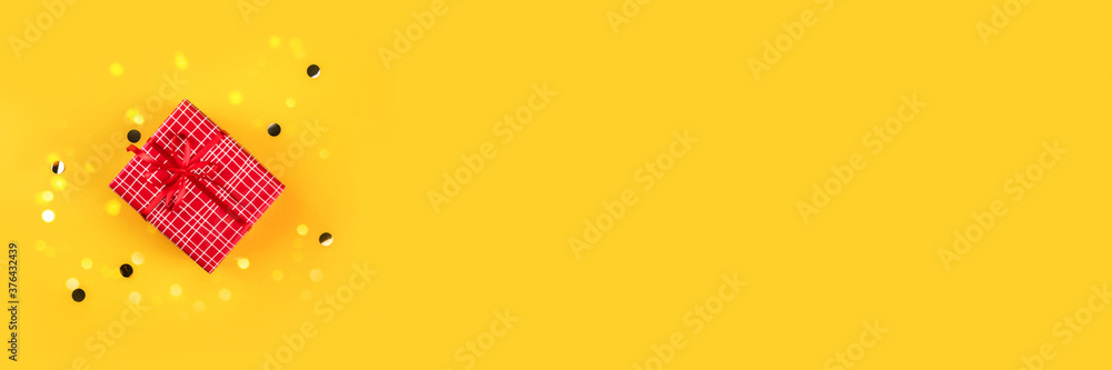 Banner made from red gift box on yellow background with golden confetti. - obrazy, fototapety, plakaty 