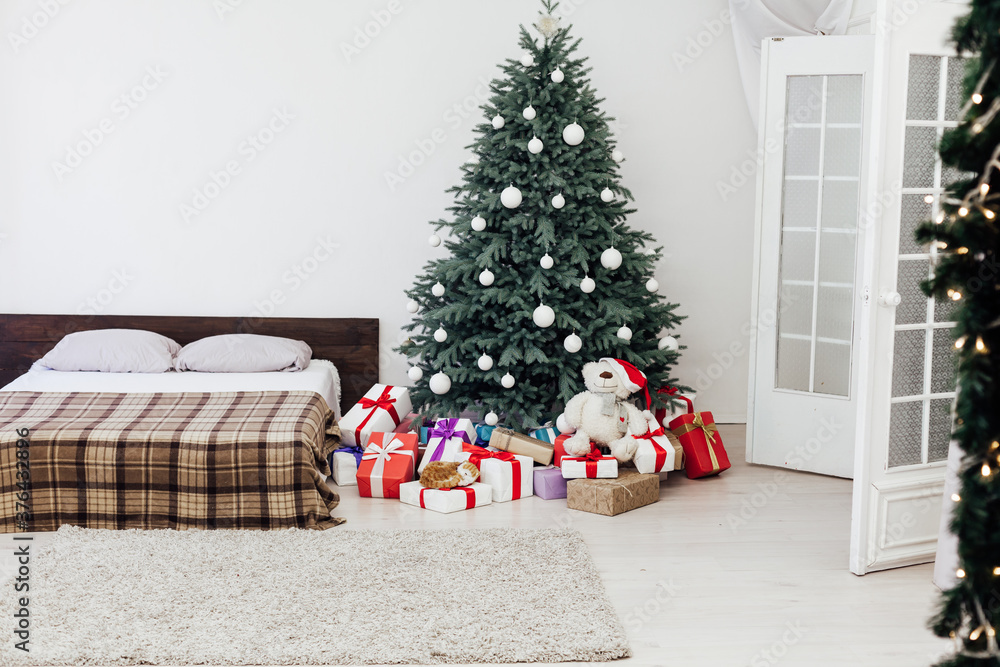 Christmas tree in the interior of the bedroom with a bed and pads for the new year Christmas tree in the interior of the bedroom with a bed and pads for the new year