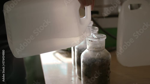 Slow-mo: Lab Technician Pours Demineralized Water to Glass Bottle