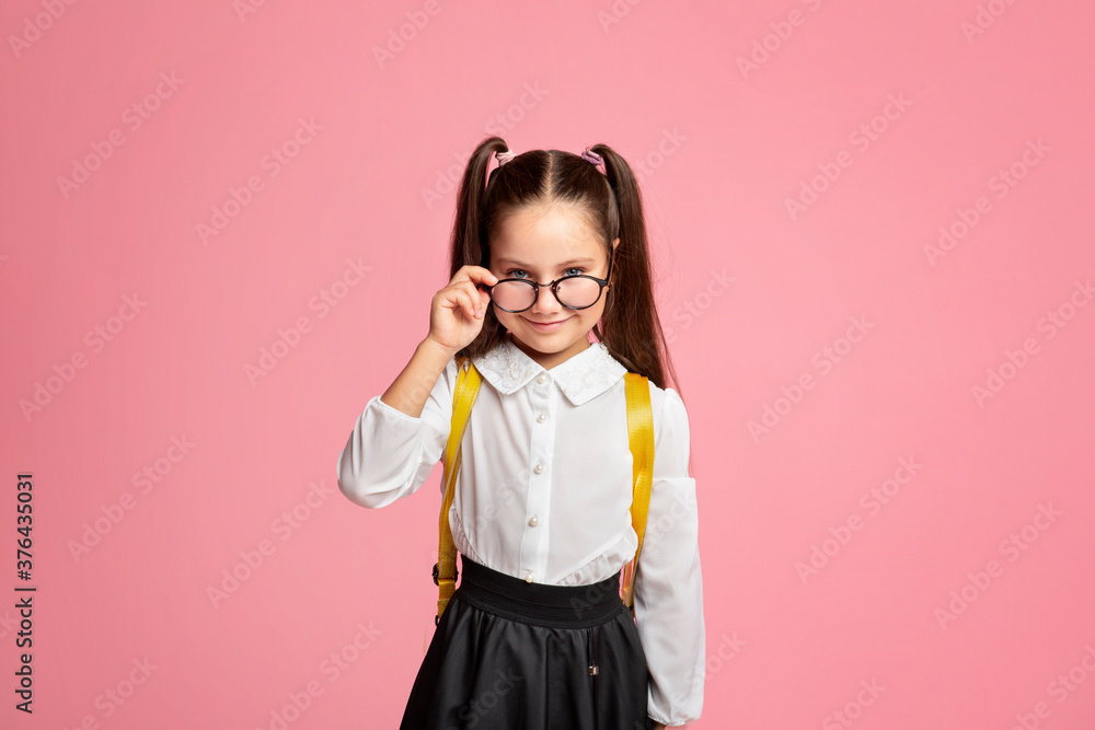 First school day. Cheerful girl in uniform takes off glasses and looks at camera First school day. Cheerful girl in uniform takes off glasses and looks at camera