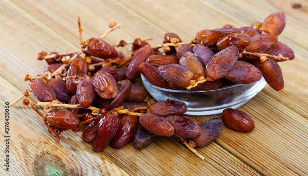 Natural dried fruits of date palm in bowl on wooden surface. Healthy superfood