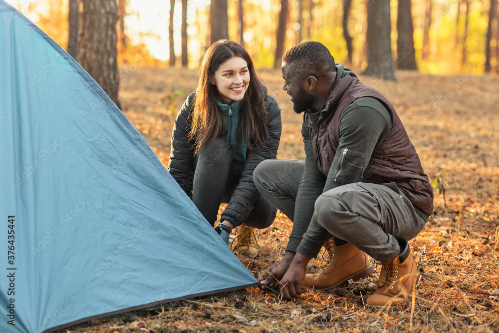 Man and woman making tent together, having conversation Man and woman making tent together, having conversation