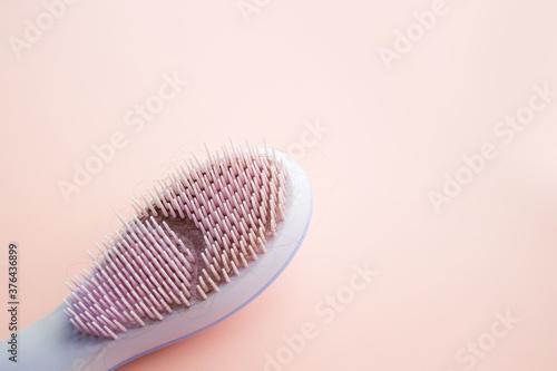 Comb with long woman hair on pink background with copy space. Hair loss problem