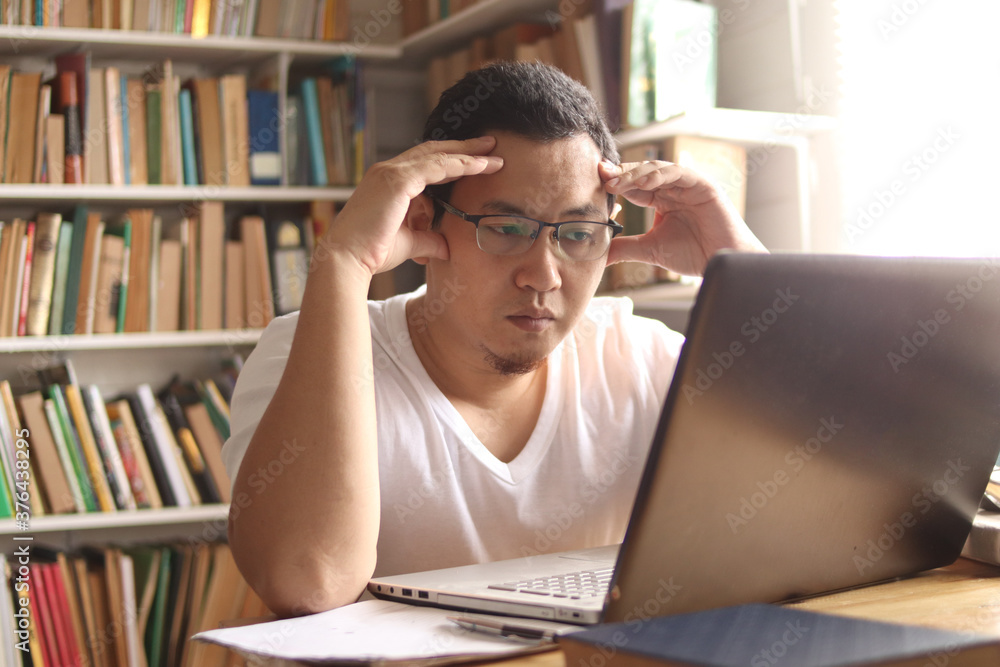 Asian muslim man studying in library, exam preparation concept. Male college student using laptop to learn online Asian muslim man studying in library, exam preparation concept. Male college student using laptop to learn online