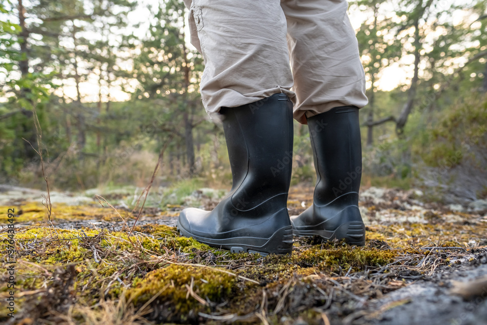 Male feet in rubber, waterproof boots, stand in the forest on a summer day. Active lifestyle. Male feet in rubber, waterproof boots, stand in the forest on a summer day. Active lifestyle.