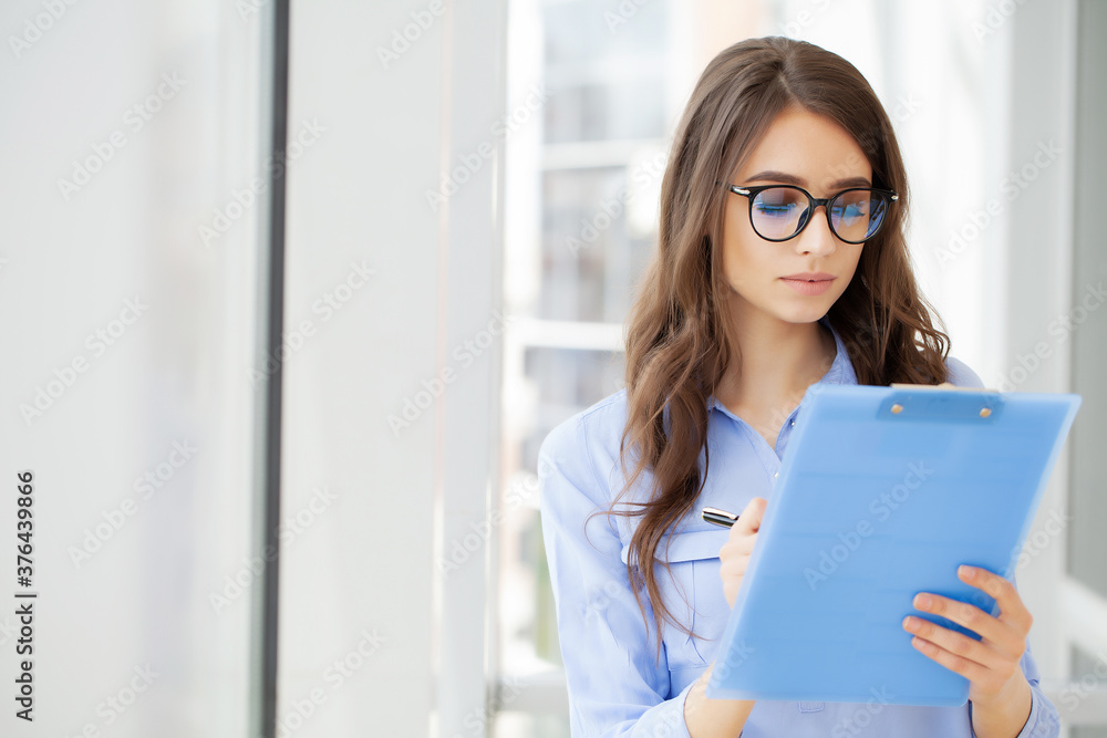 Young beautiful business woman with clipboard in the office. Young beautiful business woman with clipboard in the office.