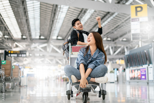 Young asian couple are happily waiting on a luggage trolley while waiting for a flight at airport terminal,opening international travel flights after the coronavirus 2019 (COVID-19) outbreak ends.