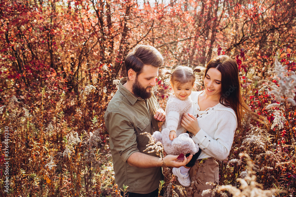 Young parents with daughter walk in autumn park, family portrait outdoors Young parents with daughter walk in autumn park, family portrait outdoors