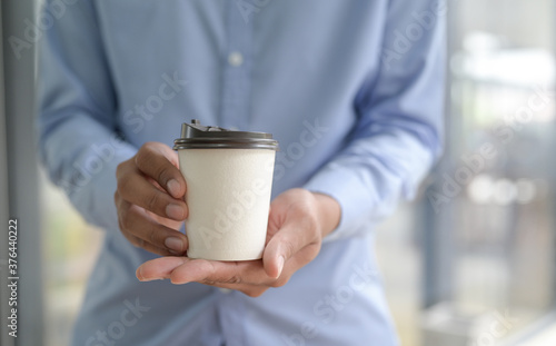 Close-up shot of Barista holding coffee cup take away in hand.