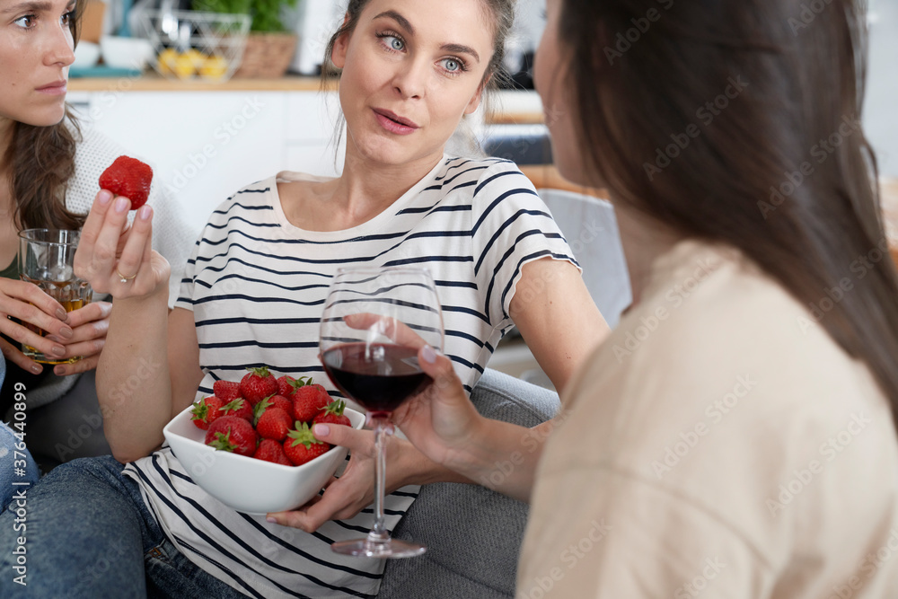 Three friends chatting and eating seasonal strawberries and drinking wine Three friends chatting and eating seasonal strawberries and drinking wine