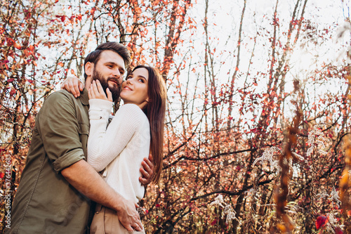 Portrait of a young couple in the autumn forest, a guy and a girl cuddling in the outdoor