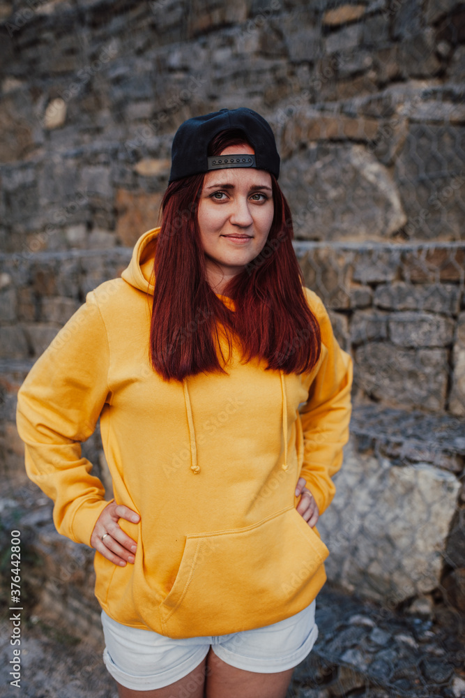 City portrait of handsome beautiful plus size girl wearing casual yellow blank hoodie or sweatshirt with space for your logo or design. Mockup for print