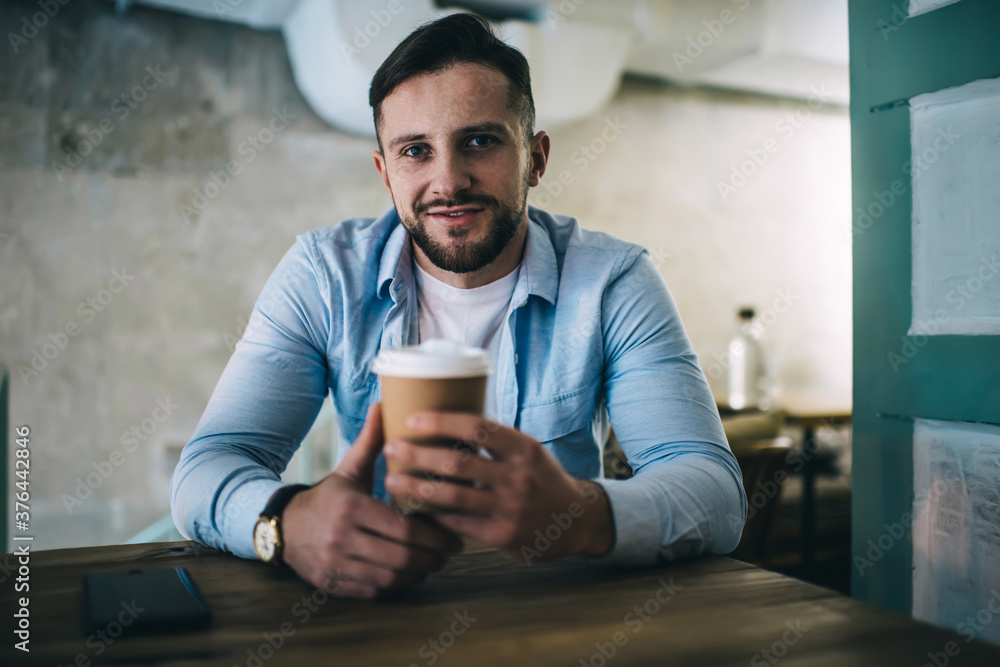 Positive man with cup of coffee sitting in cafe Positive man with cup of coffee sitting in cafe