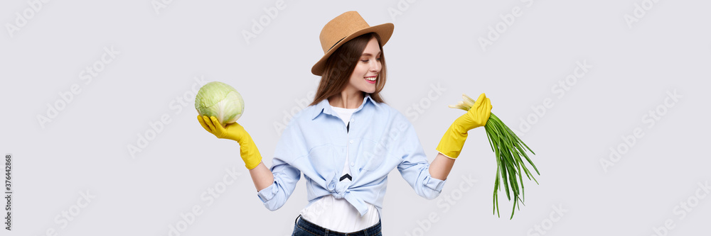 Female gardener with vegetables cabbage and onion wearing yellow gloves, hat and casual clothes, isolated on white background Female gardener with vegetables cabbage and onion wearing yellow gloves, hat and casual clothes, isolated on white background