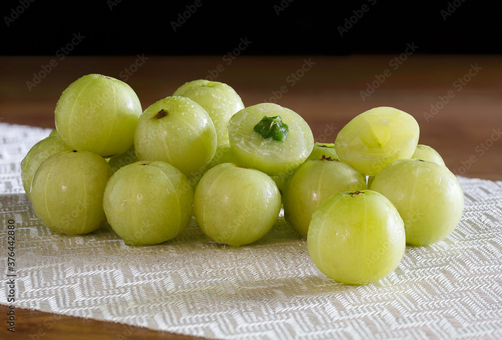 Indian Gooseberry fruit on white table cloth and wooden table Indian Gooseberry fruit on white table cloth and wooden table