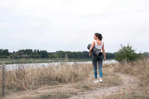 Young sporty woman doing fitness exercises near the river.