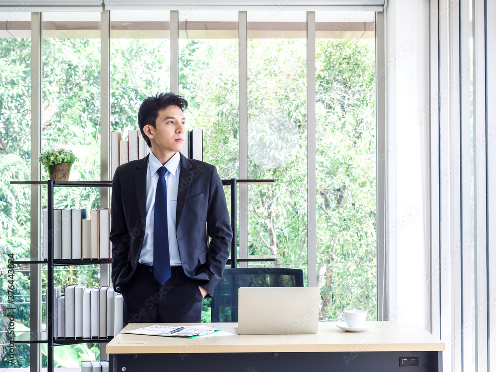 Young Asian businessman in suit working with laptop computer in office. Young Asian businessman in suit working with laptop computer in office.