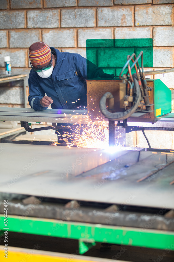 Workman in blue overalls welding some metal with sparks flying. Workman in blue overalls welding some metal with sparks flying.