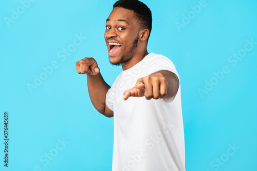 Black Man Pointing Fingers At Camera Over Blue Studio Background