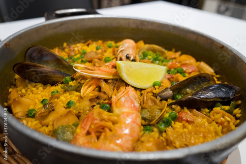 The famous traditional fish dish of spanish food and catalan cuisine - seafood paella with shrimps, mussels, fish, rice, lemon and herbs