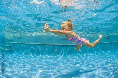 Photography Funny portrait of child learning swimming, dive in blue pool with fun - jumping deep down underwater with splashes