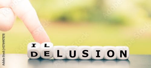 Foto Hand turns dice and changes the word delusion to illusion.