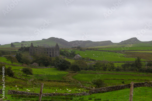 Landscape acoss the green fields of the welsh countryside to an abandoned slate mill and the mountains beyond