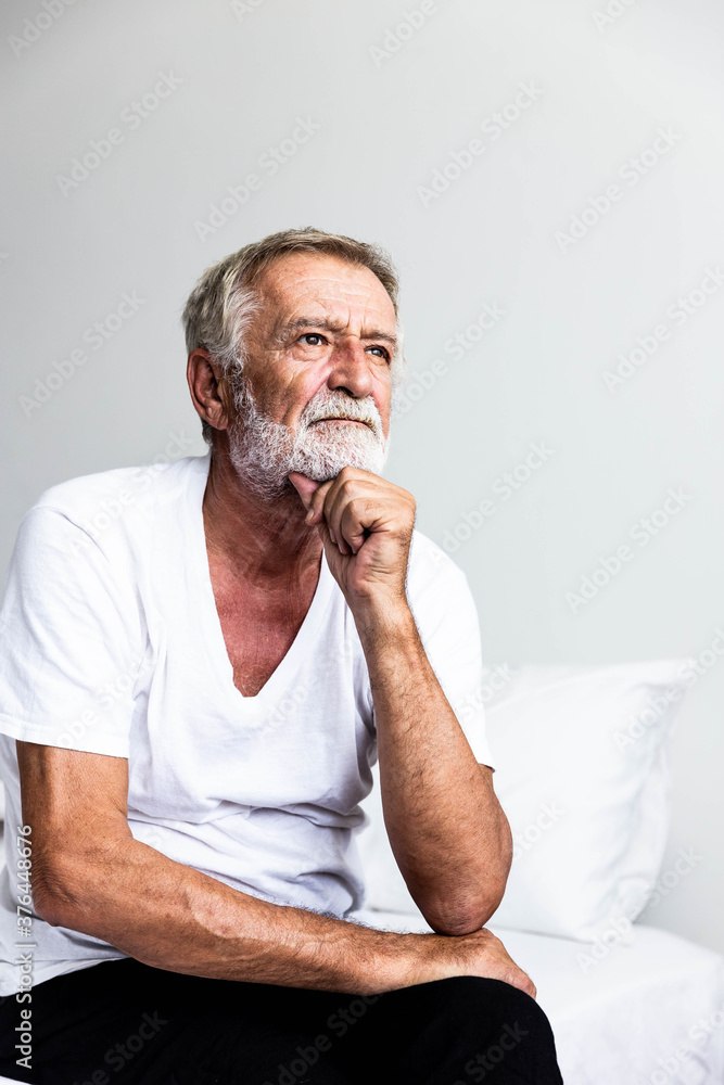 Portrait of a senior retirement man sitting and thinking alone on bed in his home Portrait of a senior retirement man sitting and thinking alone on bed in his home