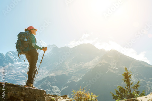 Young hiker backpacker female using trekking poles enjoying mountain view during high altitude Acclimatization walk. Everest Base Camp trekking route, Nepal. Active vacations concept image